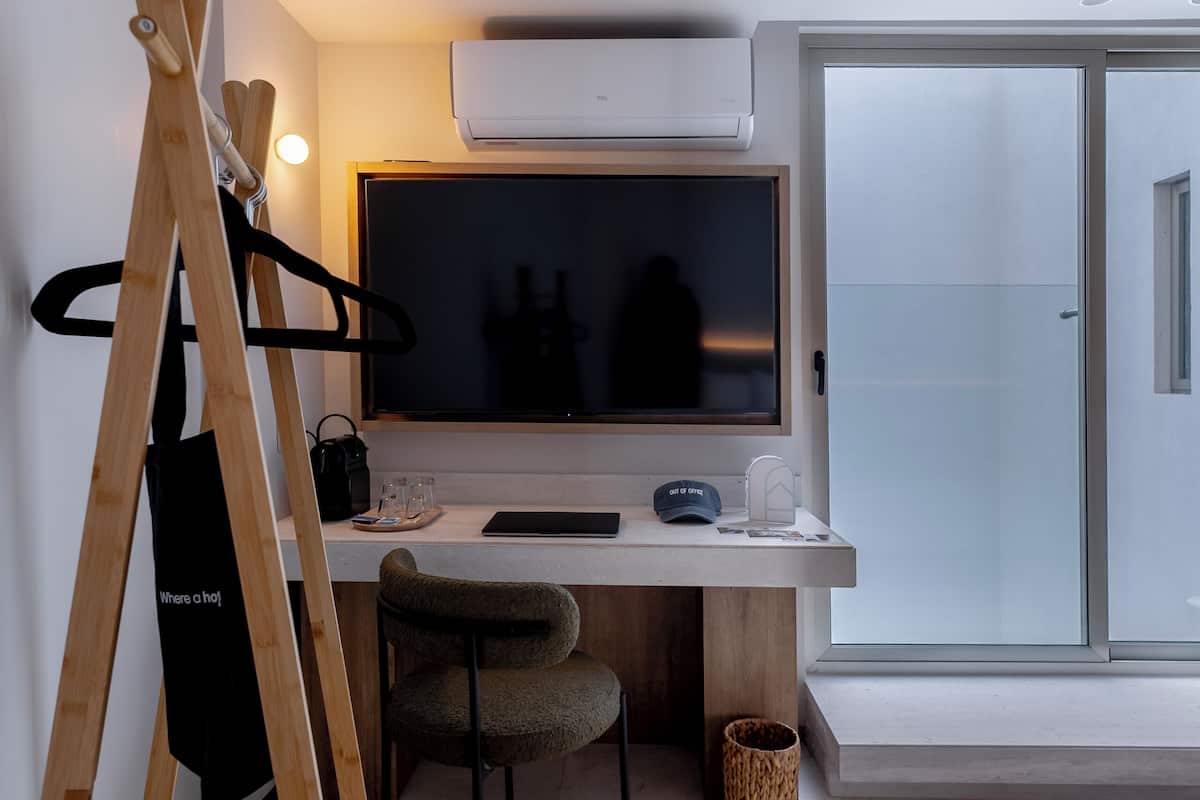 A modern hotel room with a desk, chair, and a bed.