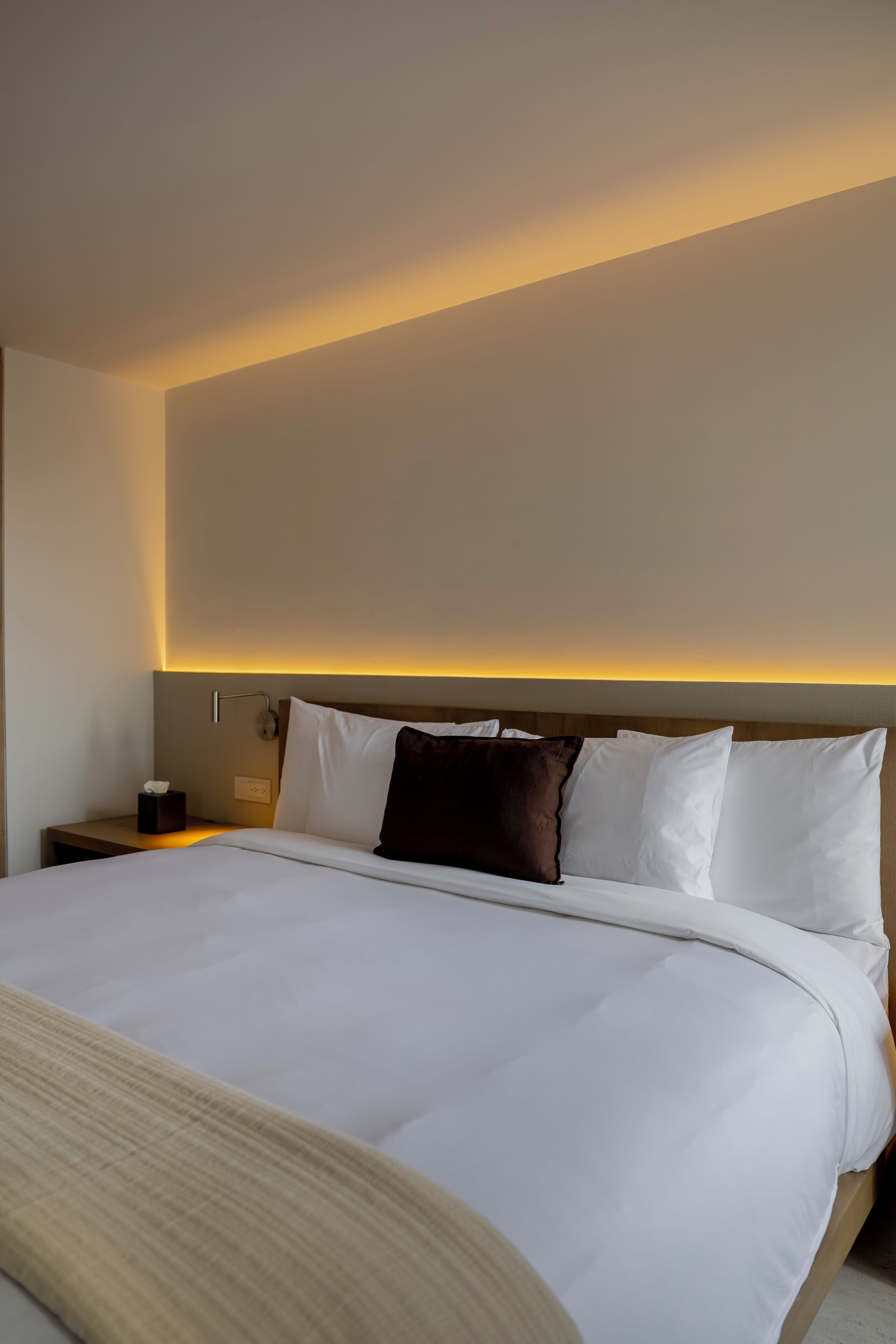 Een hotelkamer met een groot bed, een nachtkastje met een lamp en een wandlamp.