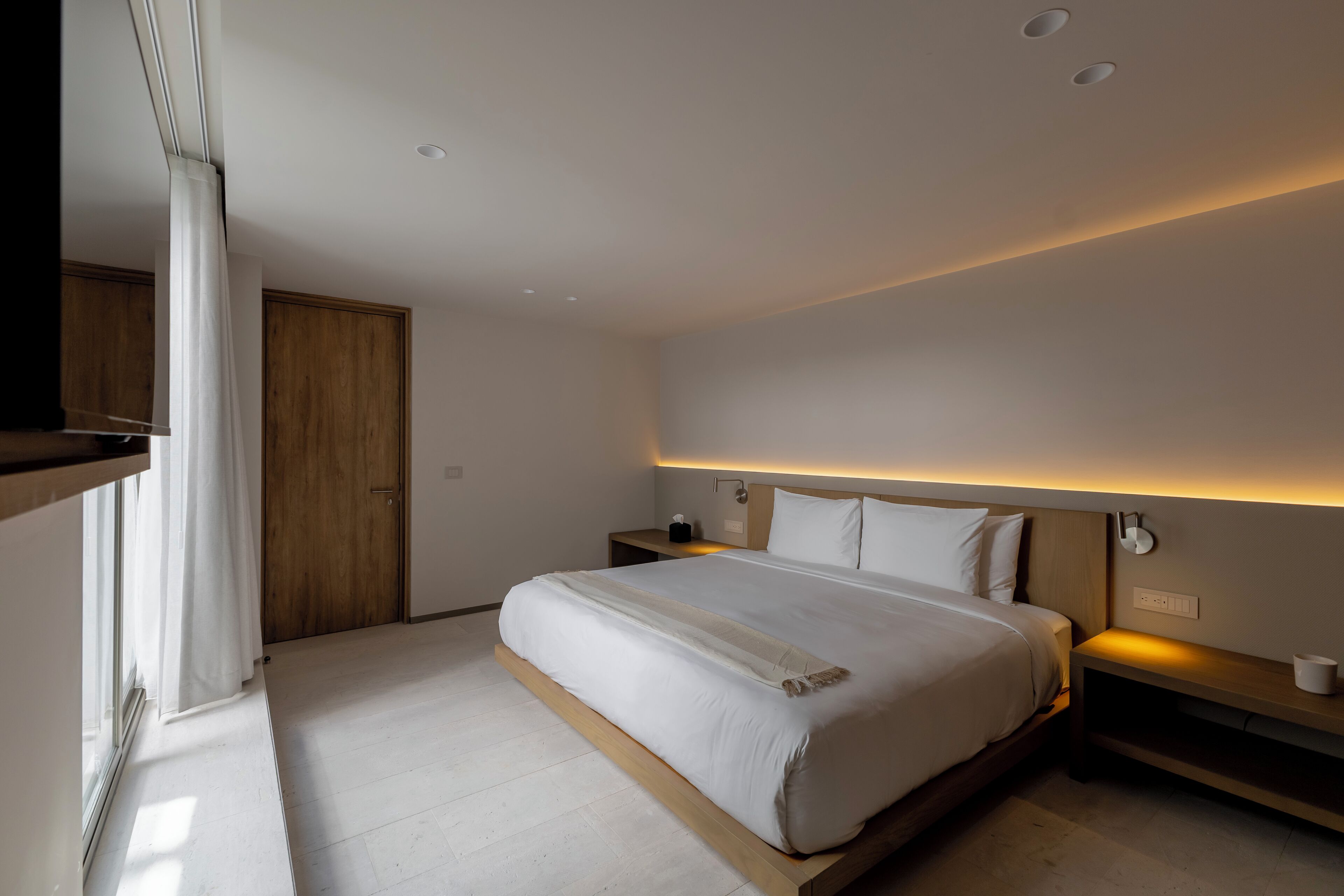 Quarto moderno com uma cama grande, mesas de cabeceira e um criado-mudo.