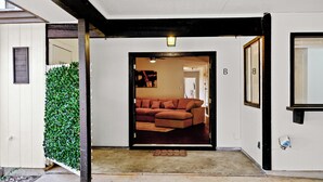 A hallway leading to a living room with a brown sofa, a welcome mat, and a door marked with a 'B'. - New Two Unit Property in North Austin I Sleep 14 (Austin)
