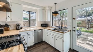 A modern kitchen with white cabinets, a stainless steel range, and a large window. - New Two Unit Property in North Austin I Sleep 14 (Austin)