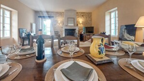 A dining area with a table set for four, a fireplace, and a television in the background. - Lovely home in Saint-Aubin-de-Cadelec with WiFi (Saint-Aubin-de-Cadelec)