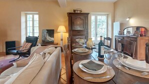 A dining area with a wooden table set for a meal, a sofa, a chair, and a lamp. - Lovely home in Saint-Aubin-de-Cadelec with WiFi (Saint-Aubin-de-Cadelec)