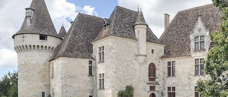 Um edifício histórico de pedra com várias torres e um pátio central.
