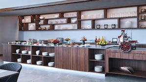 A modern kitchen with wooden shelves, a central island with food items, and a red appliance. - AC Hotel Georgetown Guyana (Georgetown)