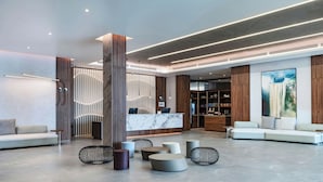 A modern lobby with a reception desk, seating areas, and a large artwork on the wall. - AC Hotel Georgetown Guyana (Georgetown)
