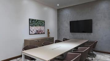 A conference room with a long table, chairs, a TV, and a cabinet with drawers.