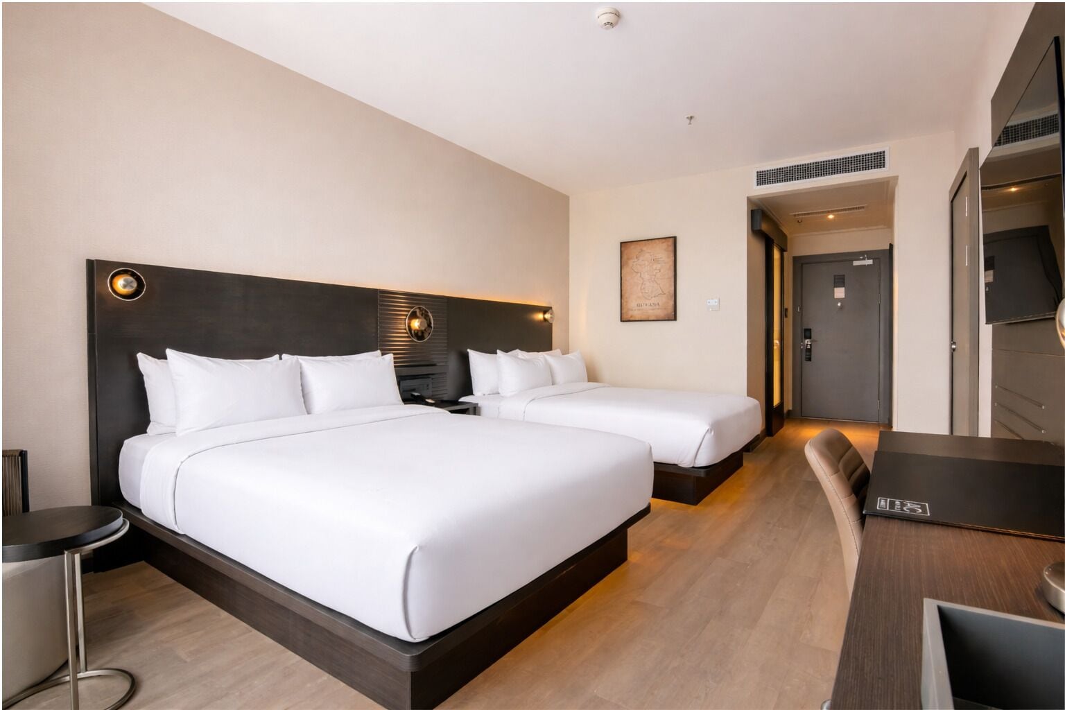 Habitación de hotel con dos camas, un escritorio y una silla.