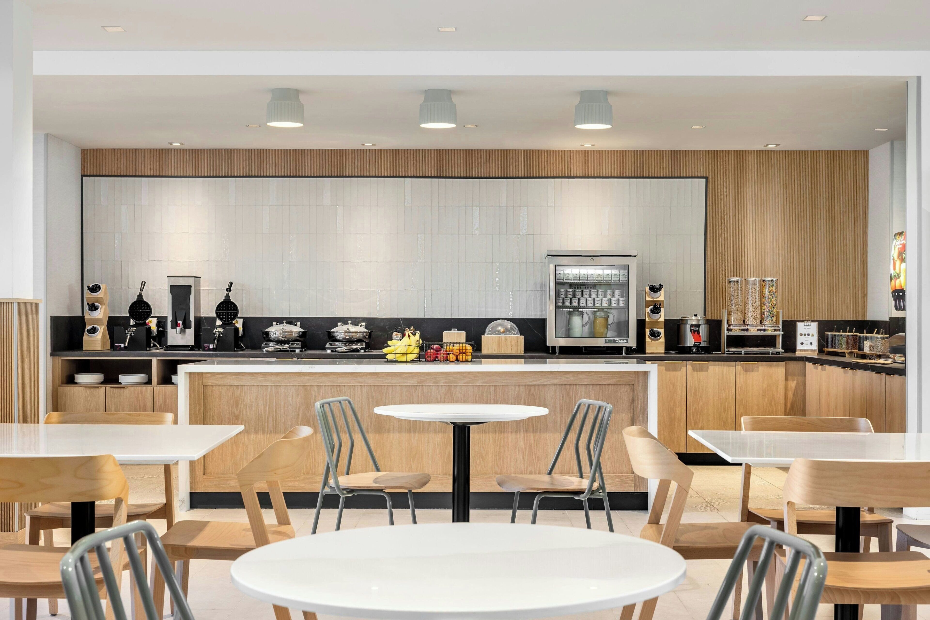 A modern restaurant with a wooden counter, white tables, and chairs.