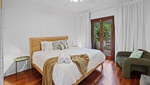 A bedroom with a bed, a chair, a small table, a ceiling fan, and a view through a glass door. - Salt Soul South Freo - 3BR (Perth)