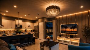 Une cuisine moderne avec des meubles blancs, des appareils en acier inoxydable et des luminaires suspendus.