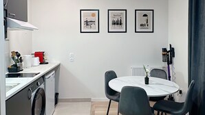 Een moderne keuken met een wasmachine, een eettafel met stoelen en drie ingelijste foto’s aan de muur.