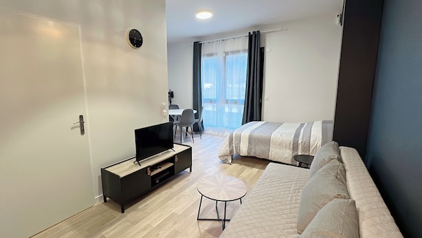 Een moderne hotelkamer met een bed, een televisie, een tafeltje en een bank.