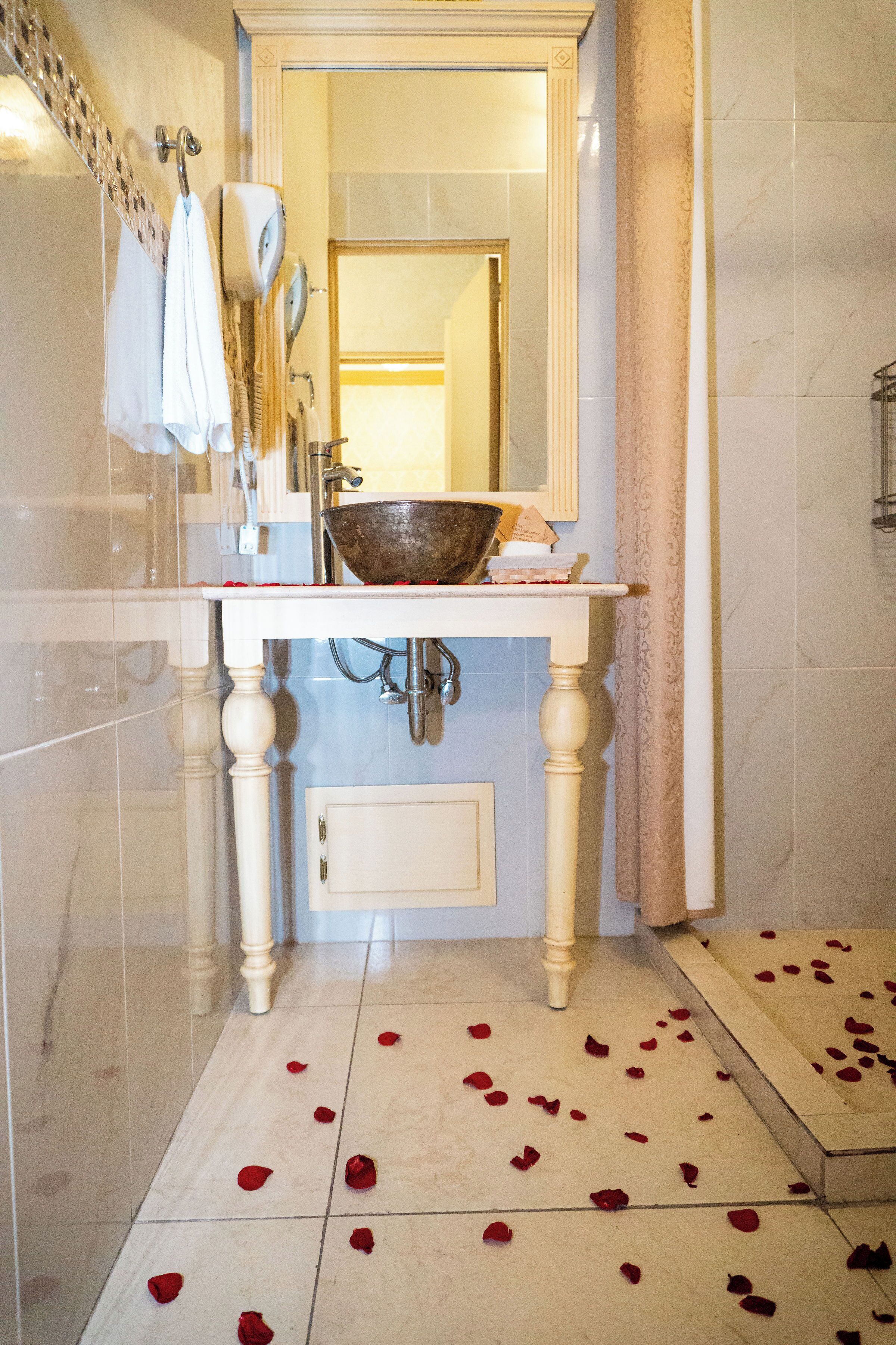 A bathroom with a white sink, a large mirror, and a decorative bowl on the counter.
