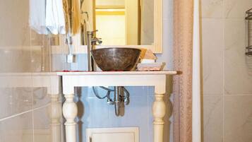 A bathroom with a white sink, a large mirror, and a decorative bowl on the counter.