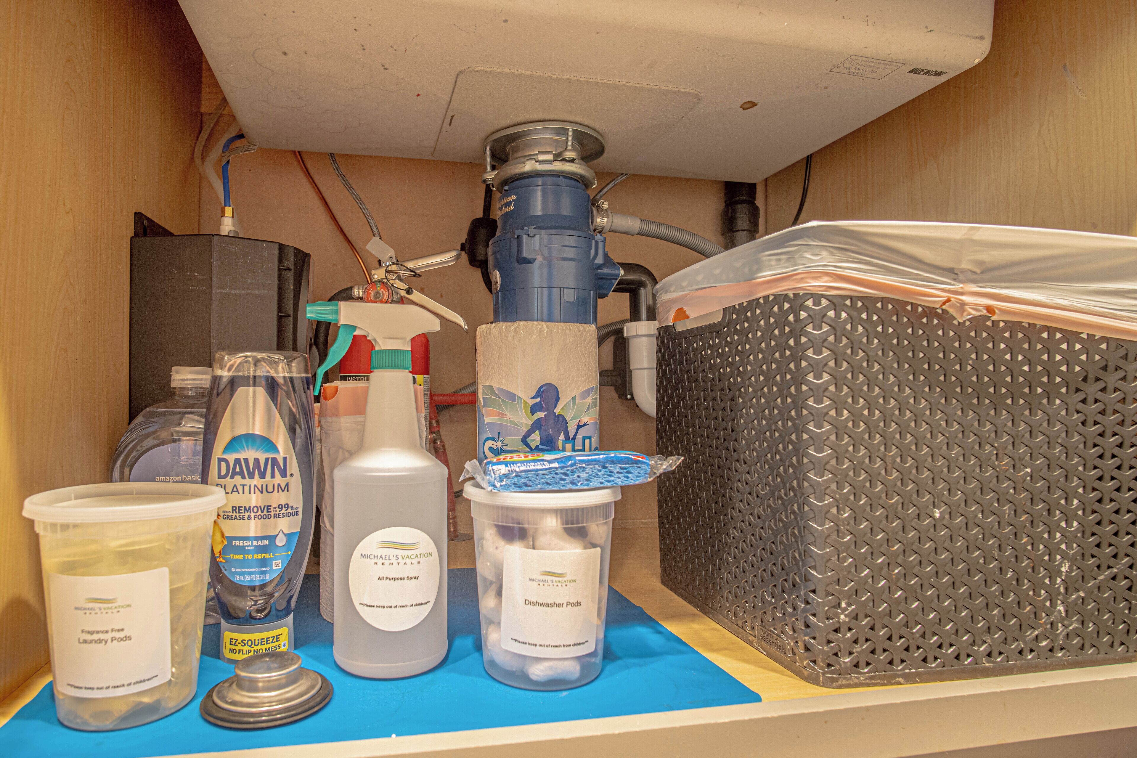 Une pièce utilitaire équipée d’un chauffe-eau, d’un lave-vaisselle et de divers produits de nettoyage.