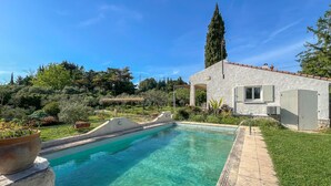 A swimming pool with a stone border, a pergola, and a white building with a window. - Awesome home in Fontvieille (Fontvieille)