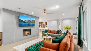 A modern living room with a fireplace, a large flat-screen TV, and a sofa set. - Foosball, Hot Tub, Big Backyard, Disneyland, AN12 (Anaheim)