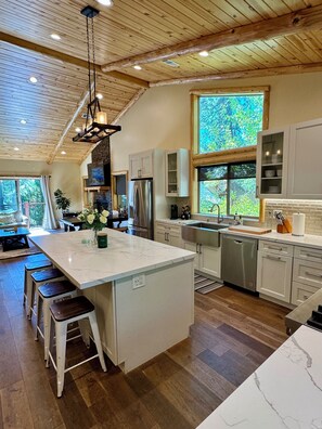 Una cocina moderna con una isla grande, techo de madera y vistas al exterior.