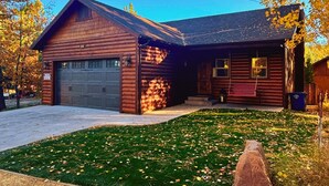 Ein rustikales Blockhaus mit Garage und überdachter Veranda.