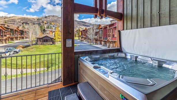 Un jacuzzi con una terraza de madera y vista a un pueblo de montaña.