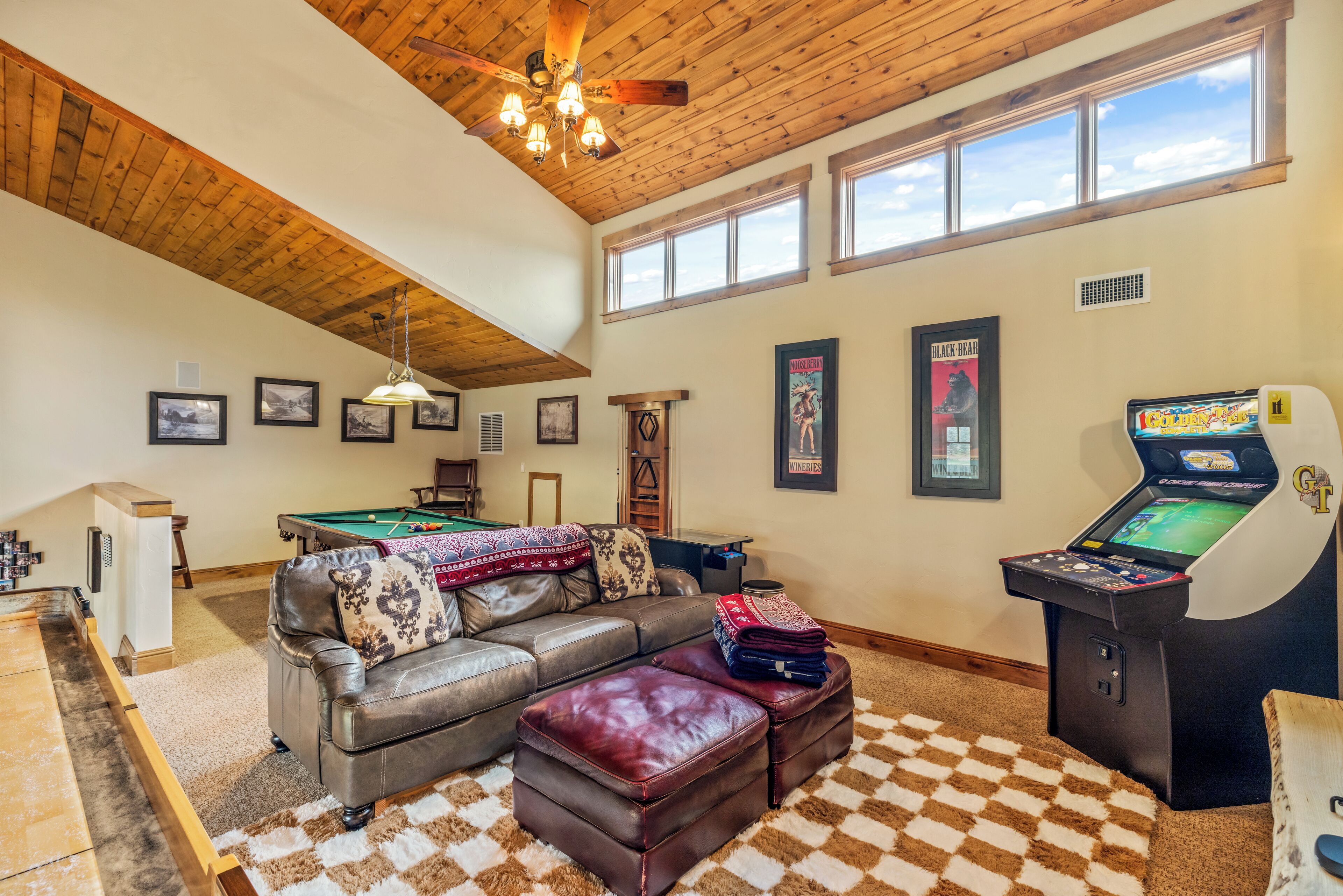 A spacious living room with a pool table, a leather sofa, and a gaming console.