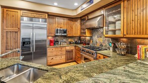 Una cocina con armarios de madera, electrodomésticos de acero inoxidable, encimeras de granito y salpicadero de azulejos.