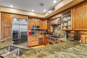 A kitchen with wooden cabinets, stainless steel appliances, granite countertops, and a tiled backsplash. - Cimarron #14 - walk to base, winter ski shuttle, private deck spa, Mountain views! (Steamboat Springs)