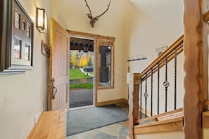 A wooden staircase with a metal railing, a deer head mounted on the wall, and a door leading outside. - Cimarron #14 - walk to base, winter ski shuttle, private deck spa, Mountain views! (Steamboat Springs)