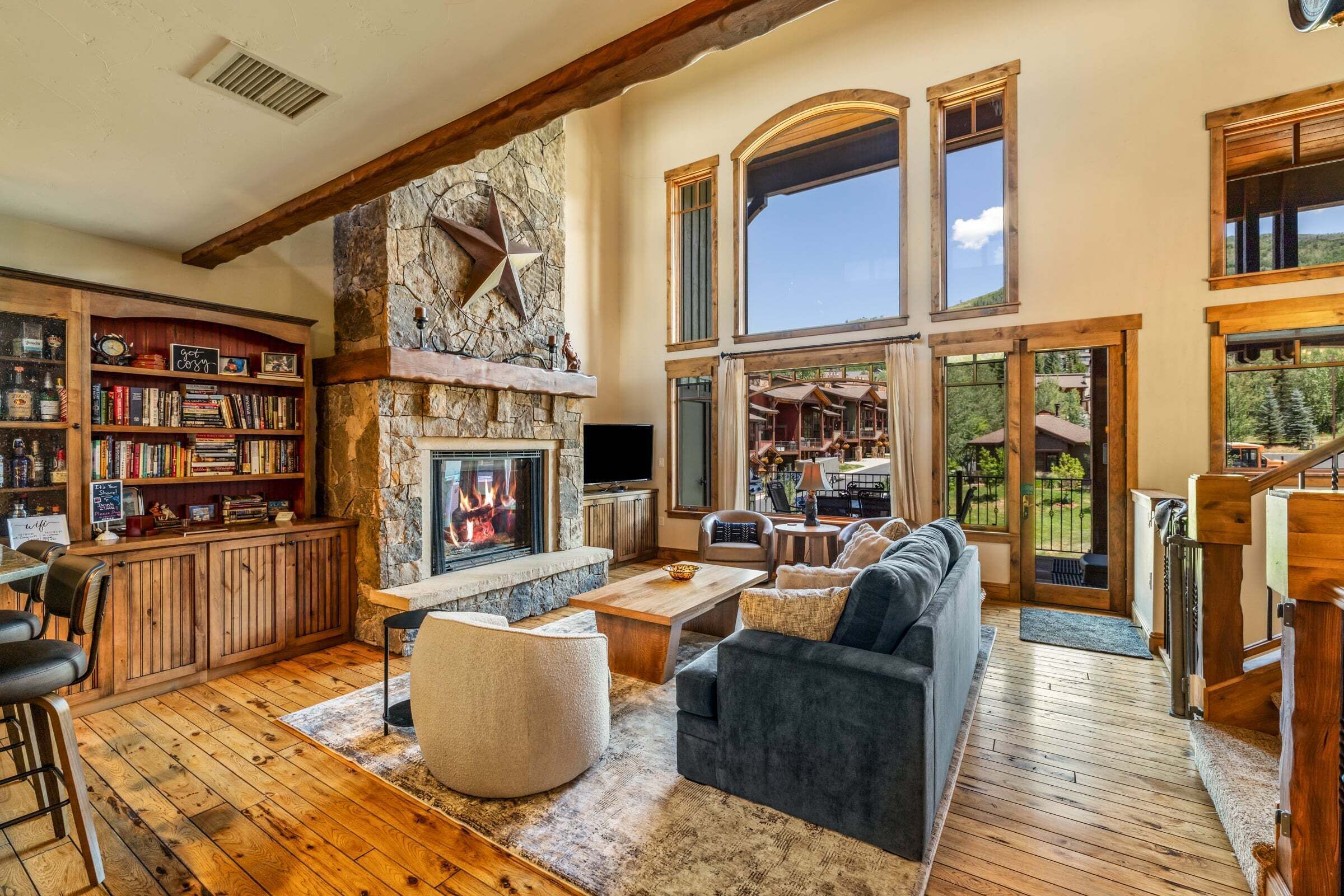 A spacious living room with a stone fireplace, a large bookshelf, and a comfortable seating area.