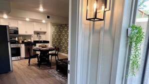 Une cuisine moderne avec des meubles blancs, un coin repas comprenant une table et des chaises, et une porte-fenêtre coulissante donnant sur un espace extérieur.
