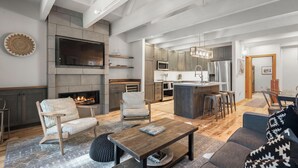 Una sala de estar moderna con chimenea, un área de cocina y un espacio de comedor.