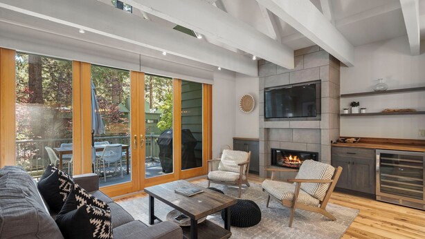Una sala de estar moderna con chimenea, puertas correderas de vidrio amplias y una zona de estar acogedora.