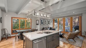 Una cocina moderna con una isla grande, electrodomésticos de acero inoxidable y una lámpara colgante.