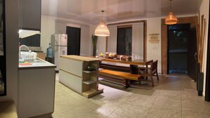 Cocina moderna con una isla central, asientos tipo banco de madera e iluminación colgante.