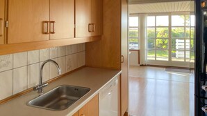 A kitchen with wooden cabinets, a stainless steel sink, and a dishwasher.