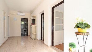 A hallway with a washing machine, a cabinet, and a potted plant on a stand. - Apartment 2411/167402 (Istria - Liznjan), 1500m from the beach (Liznjan)