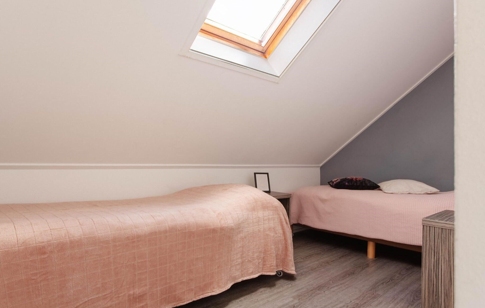 Eine kleine Einzimmerwohnung mit zwei Betten, einem Oberlicht und Holzboden.