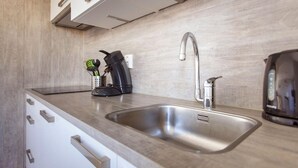 A modern kitchen with a stainless steel sink, a kettle, and a coffee maker.
