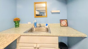 Un baño con lavamanos, espejo y dispensador de toallas.