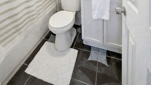 Un baño con inodoro, lavamanos y cortina de ducha.
