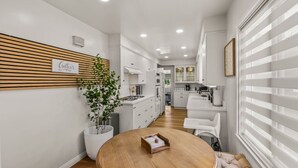 Een moderne keuken met witte kasten, een houten aanrechtblad en een eethoek met een ronde tafel.
