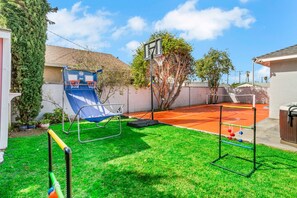 A backyard with a basketball court, a slide, and a swing set.
