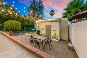 An outdoor patio with a table and chairs, surrounded by greenery and string lights. - Rooftop View, Spacious Yard, 19 min Disney, OR3 (Orange)