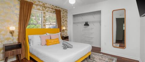 A bedroom with a bed, a ceiling fan, a wardrobe, and a mirror.
