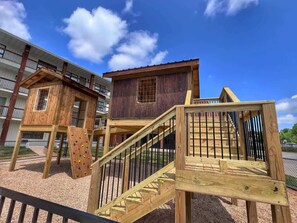Un parque infantil con estructuras de madera para escalar y una escalera.