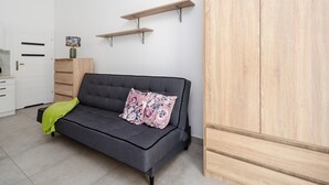 Un soggiorno moderno con un divano grigio, un mobile contenitore in legno e due mensole a parete.