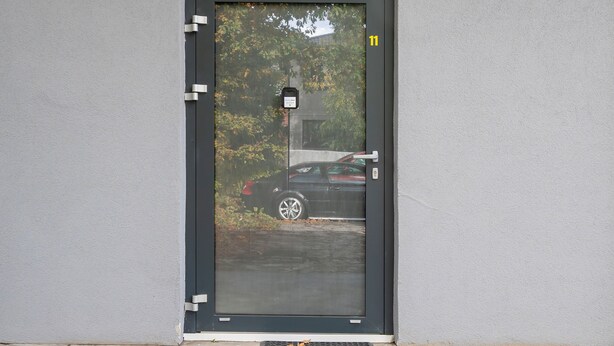 Una porta con una targa con il numero 11, una serratura a codice numerico e un gradino in metallo per l'accesso.