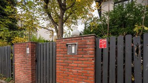 Un muro de ladrillo con un teclado electrónico y un letrero que indica un estacionamiento.