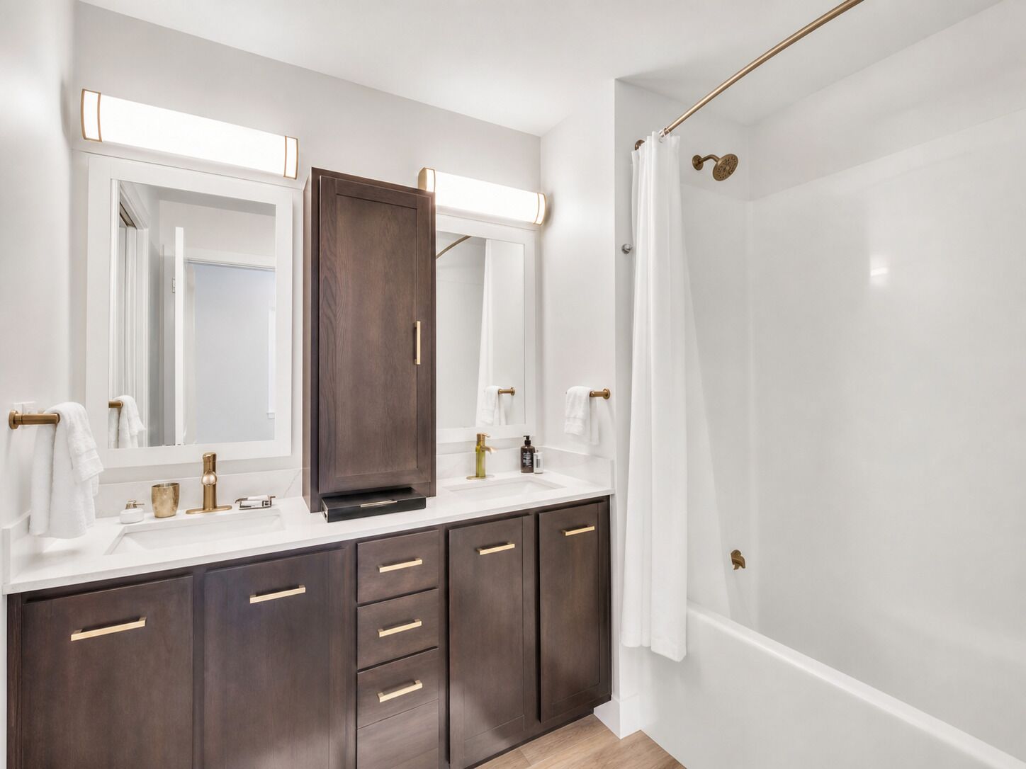 Un baño moderno con un espejo grande, un tocador de madera oscura, un lavabo blanco y una zona de ducha.